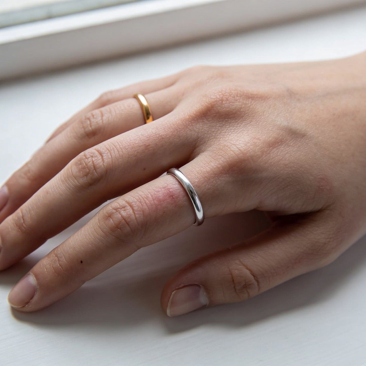 Test or vs argent : main portant une bague dorée et une bague argentée pour identifier le sous-ton de peau